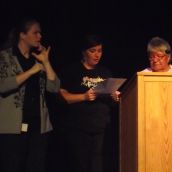 An important part of the assembly was the reading of a joint statement from the Raise the Rates campaign, here represented by Liisa Schofield (centre), and the North Shore Tribal Council, represented by Julia Ozawagosh (right), declaring support for First Nations control over disability benefits and all other social assistance on reserves, and opposition to the merger of OW and ODSP. As this photo shows, the entire event was translated into American Sign Language. (Photo by Scott Neigh)