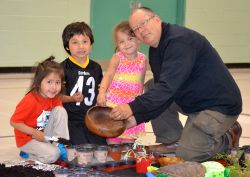 Local Ojibwe Artist and Educator, Will Morin plants sweetgrass seeds with FDK students, M'Komii Morin, Ethan McNichol and Sierra Pitawanikwat.