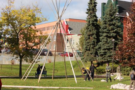 People putting up the teepee in Memorial Park. (Photo by Larson Heinonen)